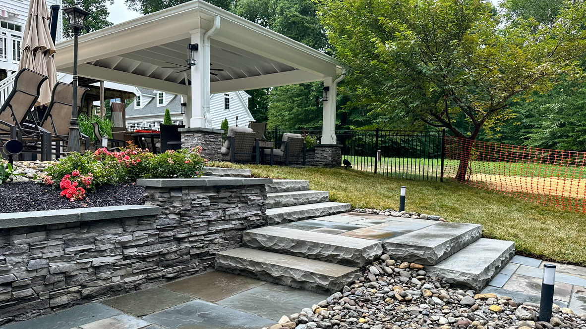 Natural stone steps, retaining wall, planting beds, and pavilion completed by Brennan's Landscaping
